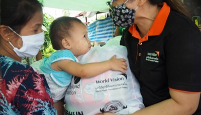 A worldvision employee giving something to a child