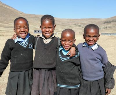 Four Childrens with school uniform are Smiling.