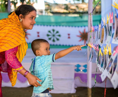 A child pointing his hand in some photos with his mom.