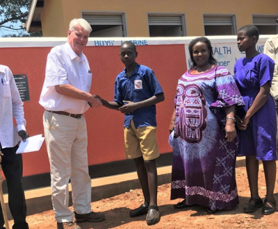 A man is shaking hand with a boy with some people