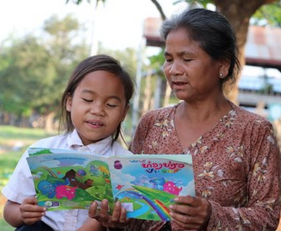 Girl from Laos reading a children's story book with her grandmother