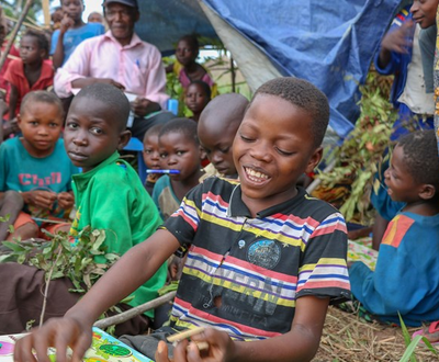 A child, surrounded by others, works on puzzles in one of four Child Friendly Spaces established in Democratic Republic of Congo