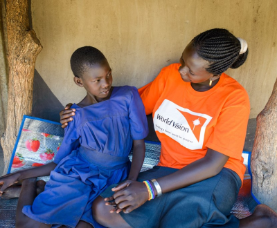 Six World Vision staff in orange tshirts in front of a stand volunteering at a World Vision event