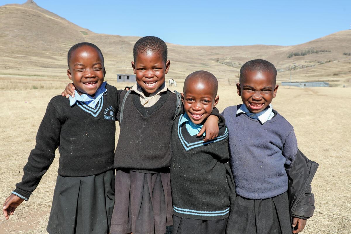 Four Childrens with school uniform are Smiling.