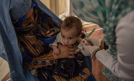 A child in Afghanistan is tested for malnutrition using a MUAC tape.