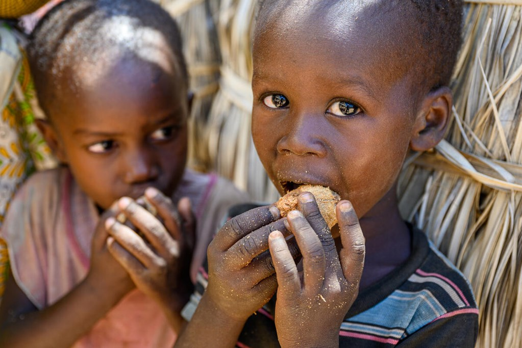 Two Childrens are eating some nuts.