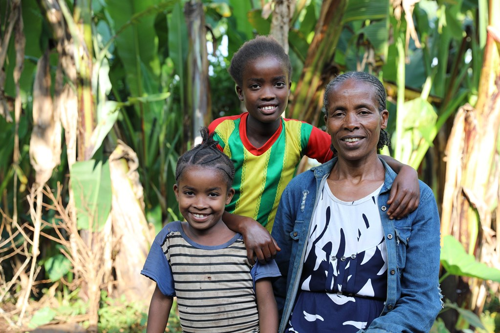 A mother from Ethiopia and her two daughters smiling at the camera