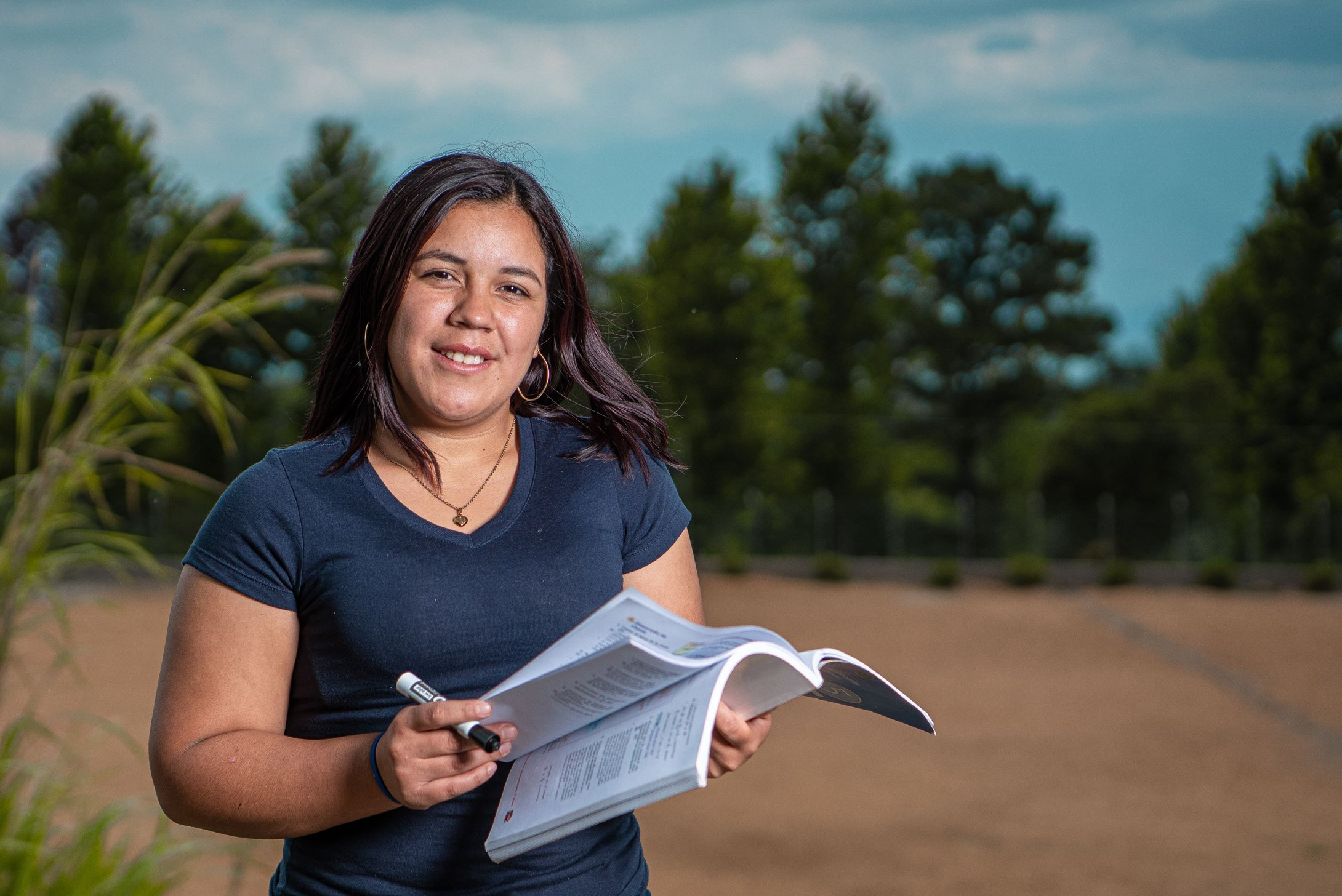 Woman from Honduras flicking between the pages of a book and looking at the camera.