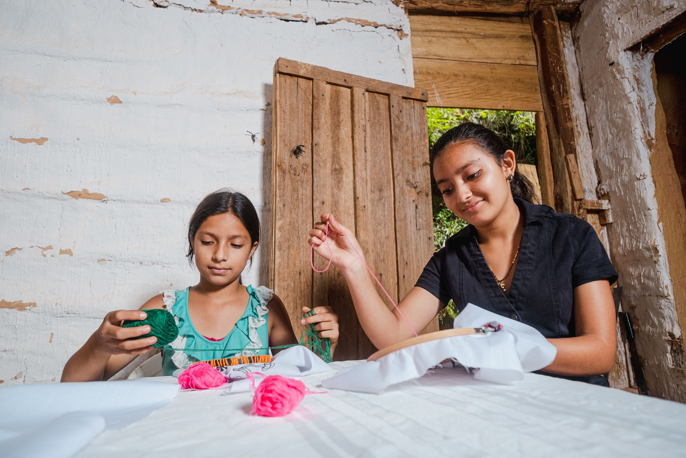 Sponsored girl Evelyn and her sister sewing a piece of cloth.