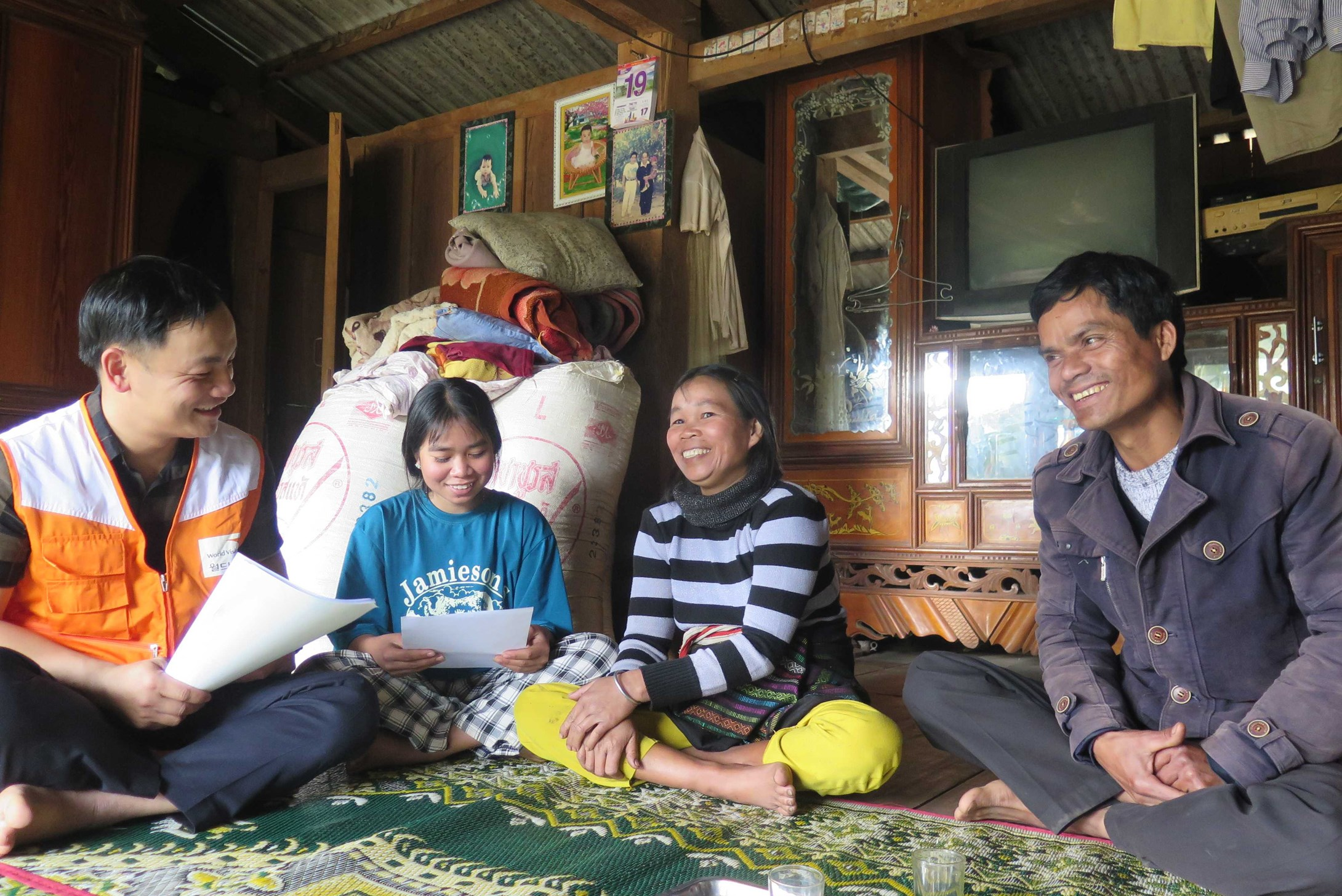 A Vietnamese family of three sitting around a table and chatting to a World Vision volunteer