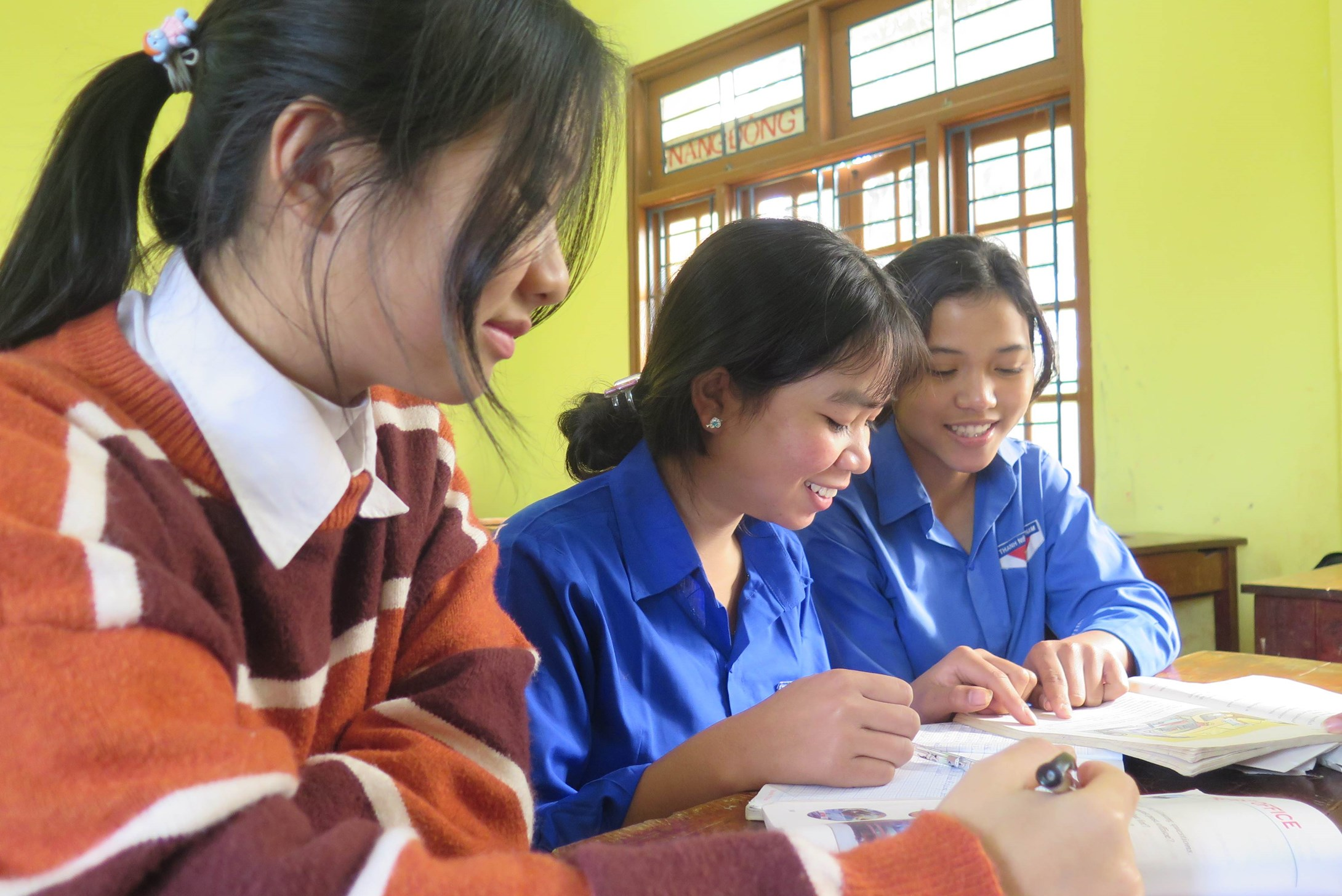 Three girls from Vietnam taking notes in their class