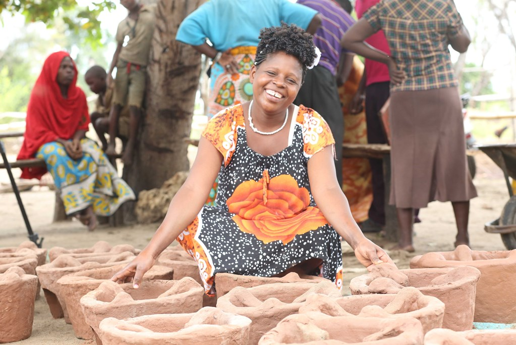 A women siting near some mud pots.