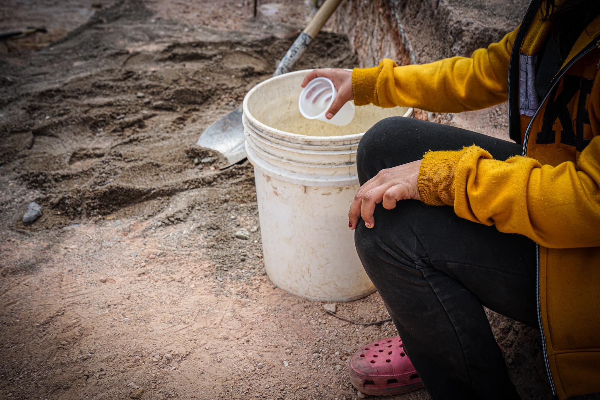 In Los Pinos, Honduras, a girl collects water with a bucket, close to the location where a new water tank for her community will be built.