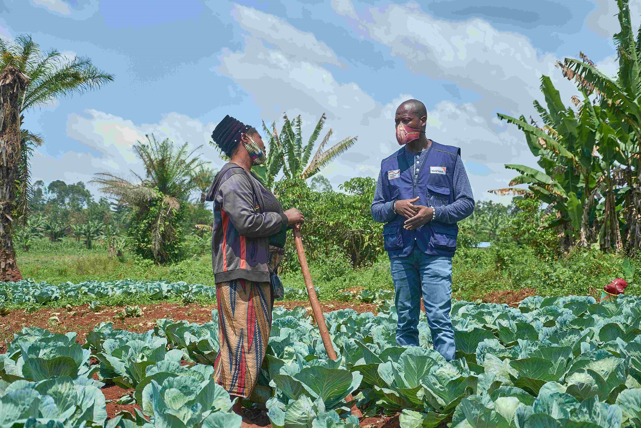 Female farmer Chantal from DRC talking to a World Vision representative in her farm.