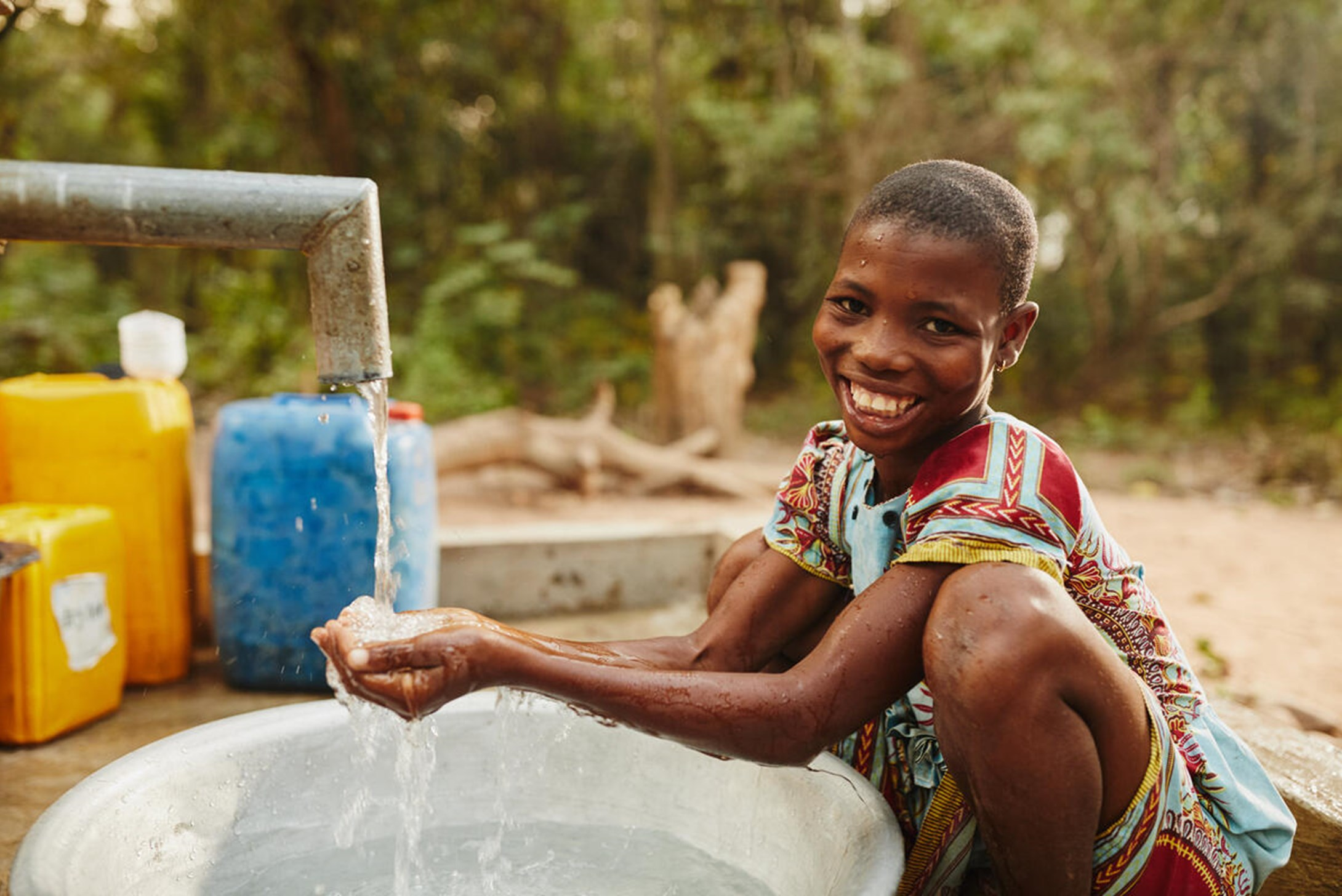 Woman collecting water in her hands from installed Water pump in Ghana.