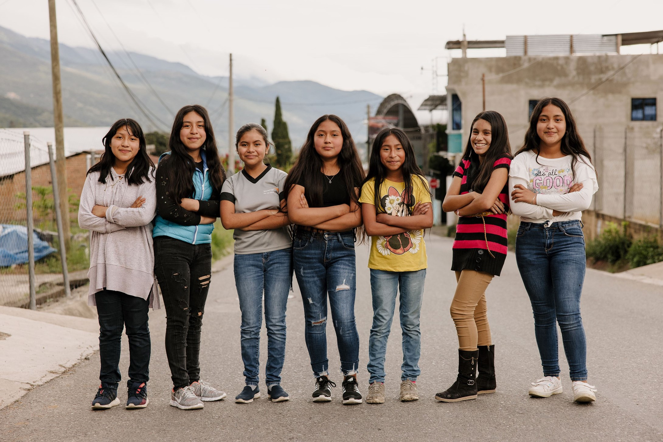 A group of girls from Guatemala standing with their arms crossed in a road