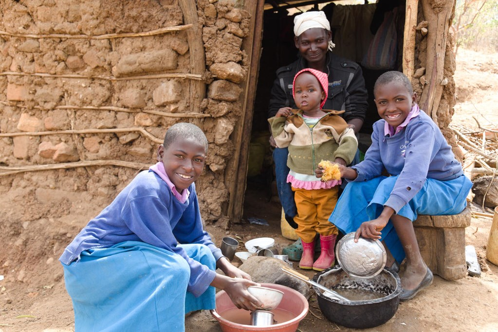 Anastacia from Kenya and her daughters wash dishes after eating a small ration of maize.