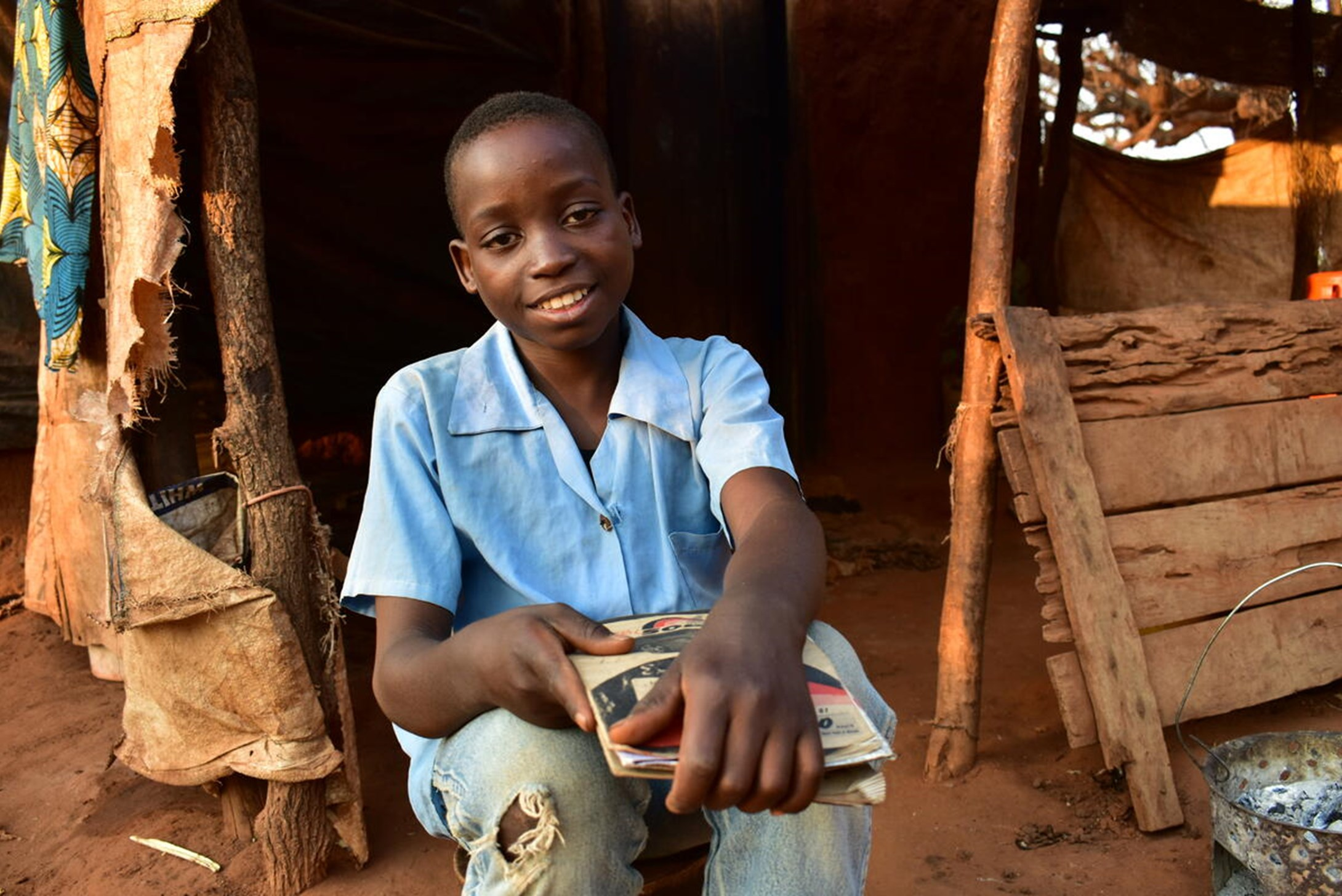 12 years old Swangirai from Zambia is healthy and is sitting with a book in his hand